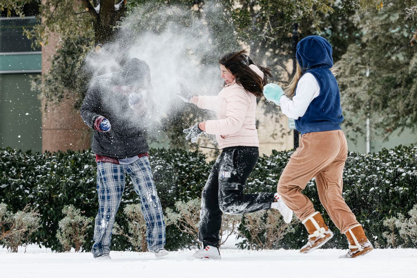 Erik Lara, left, reacts to a snowball dump from Alyssa Gonzalez, center, and Merlyn Montoya...