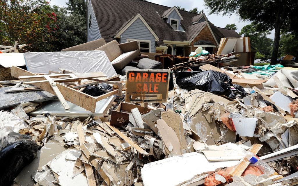 In this Sunday, Sept. 3, 2017, file photo, a garage sale sign stands in a pile of debris...