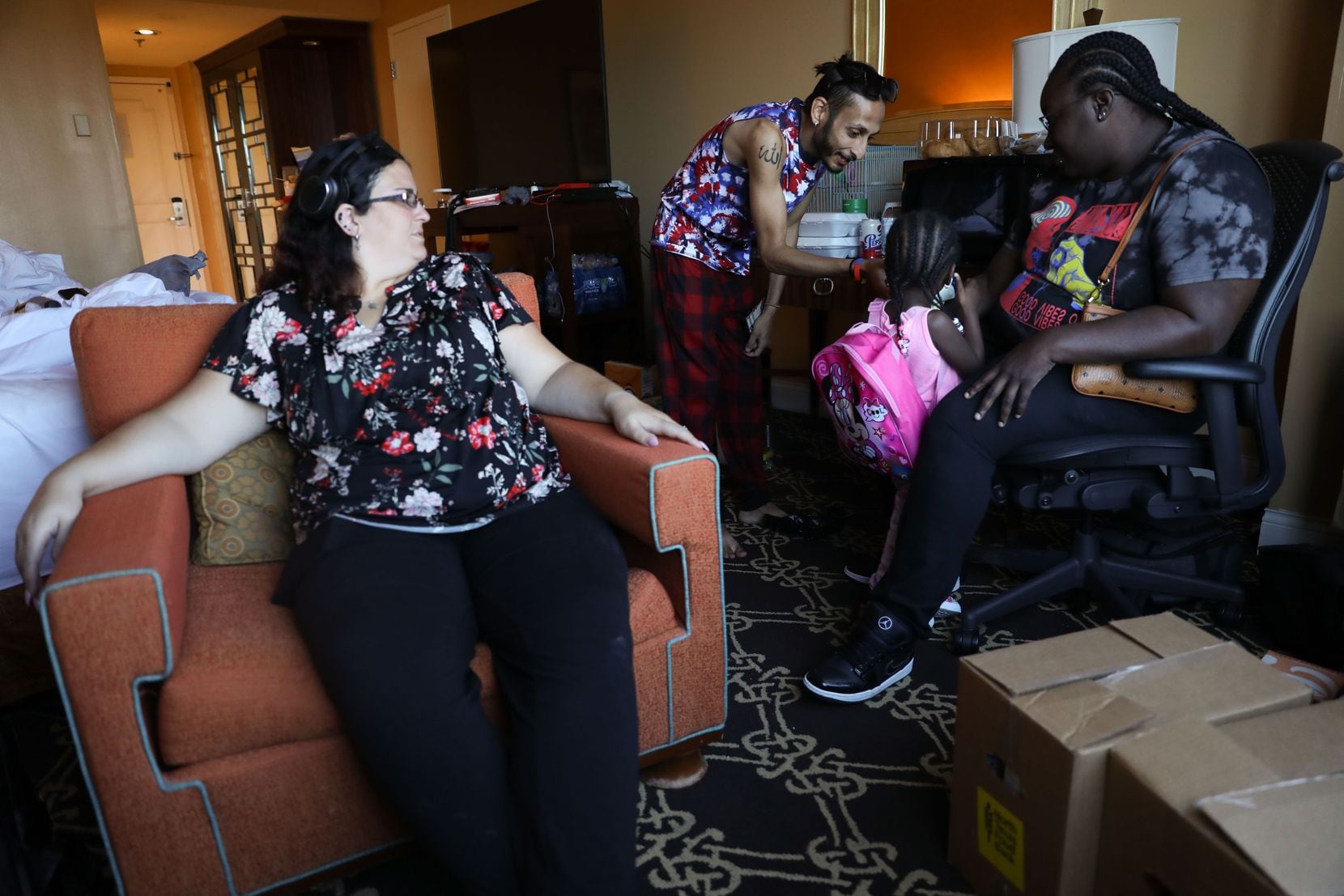 Rahim Budhwani (center) offers snacks to Aubrey Hernton, 2, in his and his fiance, Sarah Shuker's (left), hotel room at the Hilton Anatole on October 11, 2021. Aubrey's mother, Christina Hernton (right), was a neighbor who also was left without a home after the explosion. They were not close before, but since the event consider each other "family." (Liesbeth Powers/Special Contributor)