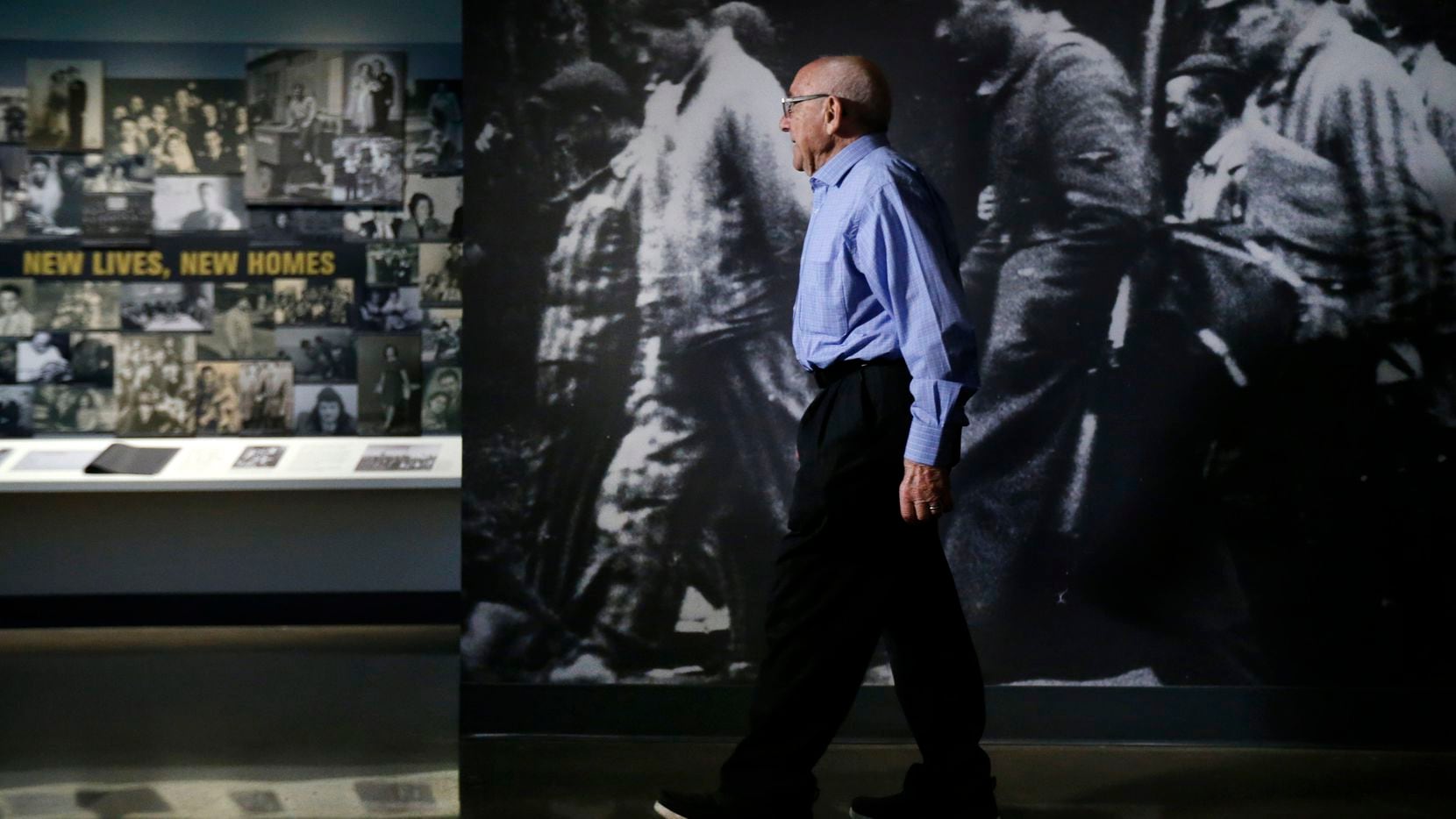 Holocaust survivor Max Glauben walks past a life-sized photo of prisoners on a death march...