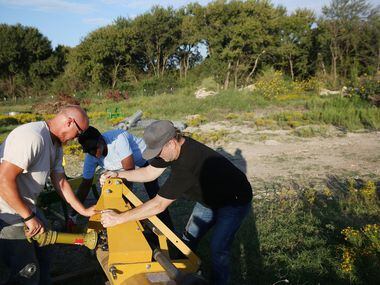 John Treffinger (from left), farm manager Kim High and Daron Babcock attempt to attach a...