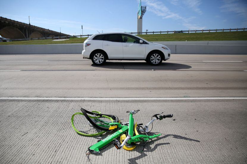 The mangled remains of a LimeBike rental bike lie alongside I-35E in downtown Dallas on Nov....