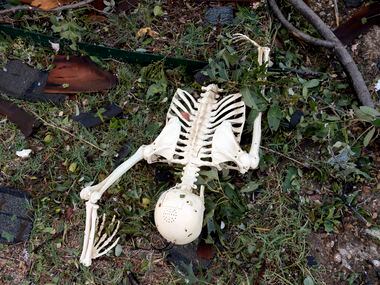 A Halloween decoration fake skeleton lies amid debris in the front yard of Brett and...