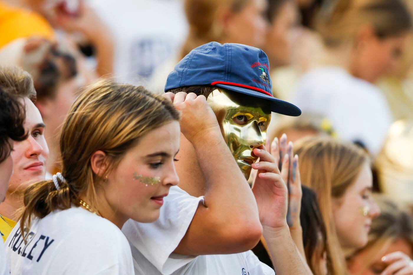 A Highland Park student puts on a gold mask during the second quarter of the season-opening...