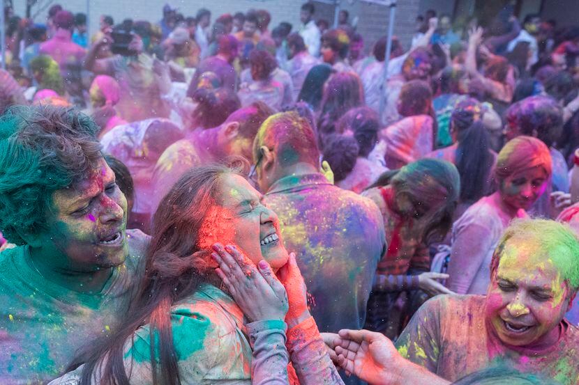 Bharat Agarwal, left, holds Natasha Bagaria as color powder is smeared on her face during...
