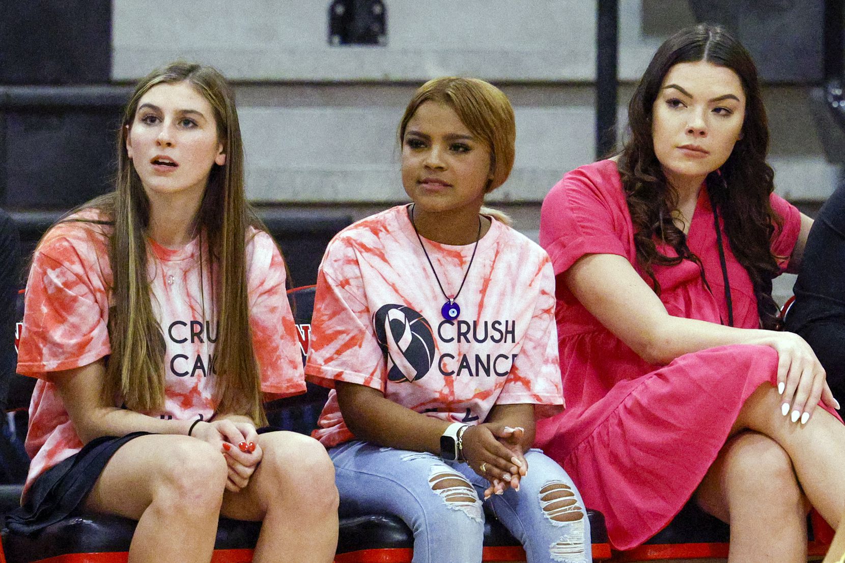 Team managers Nayeli Soto (center) and Emily Mabry (left) sit alongside assistant coach...