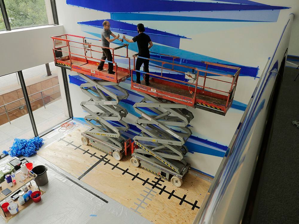 Texas artist Aaron Parazette, left, and assistant Martin Ivy put finishing touches on the...