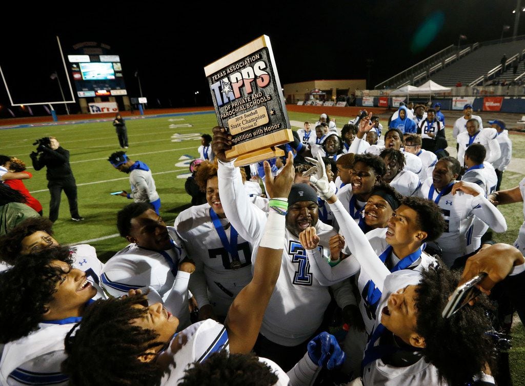Trinity Christian's head coach Andre' Hart celebrates with the team as he passes the trophy...