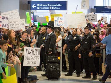 Police keep a walkway clear in the international arrivals hall at DFW International Airport...