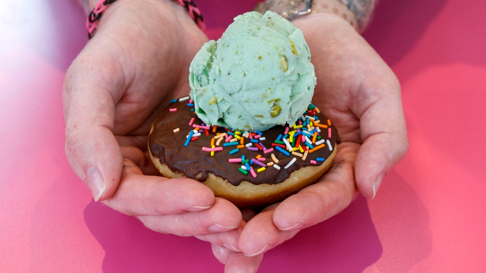 Chef Parker Howard holds a vegan chocolate glazed doughnut with sprinkles and a scoop of...