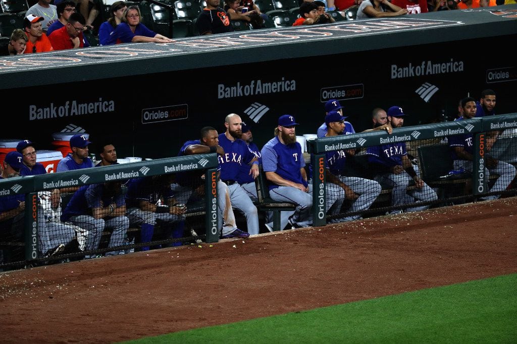 BALTIMORE, MD - JULY 20: Members of the Texas Rangers look on from the dugout in the ninth...