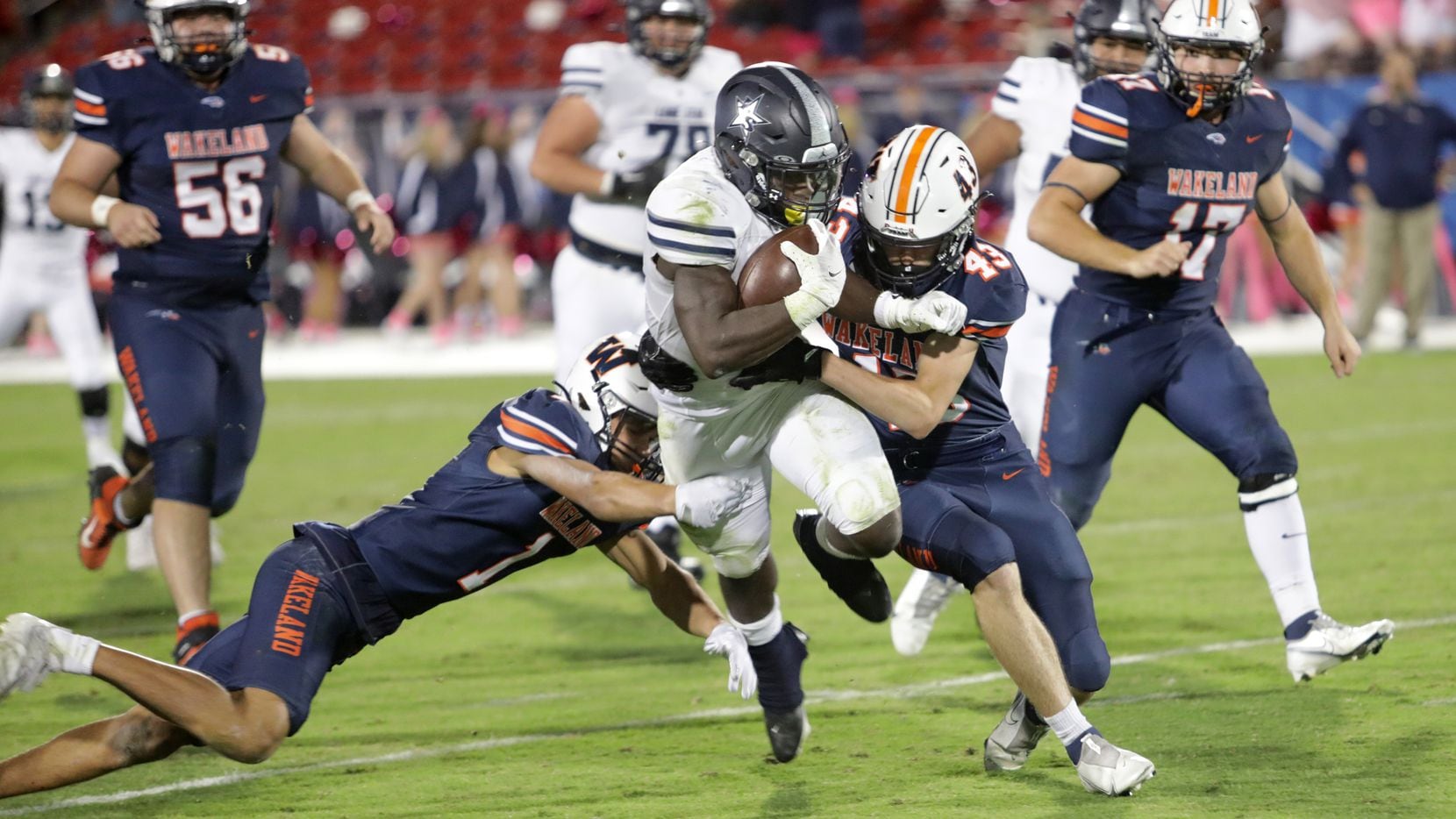 Lone Star player #2, Ashton Jeanty, is brought down by Wakeland players #1, Davion Woolen,...
