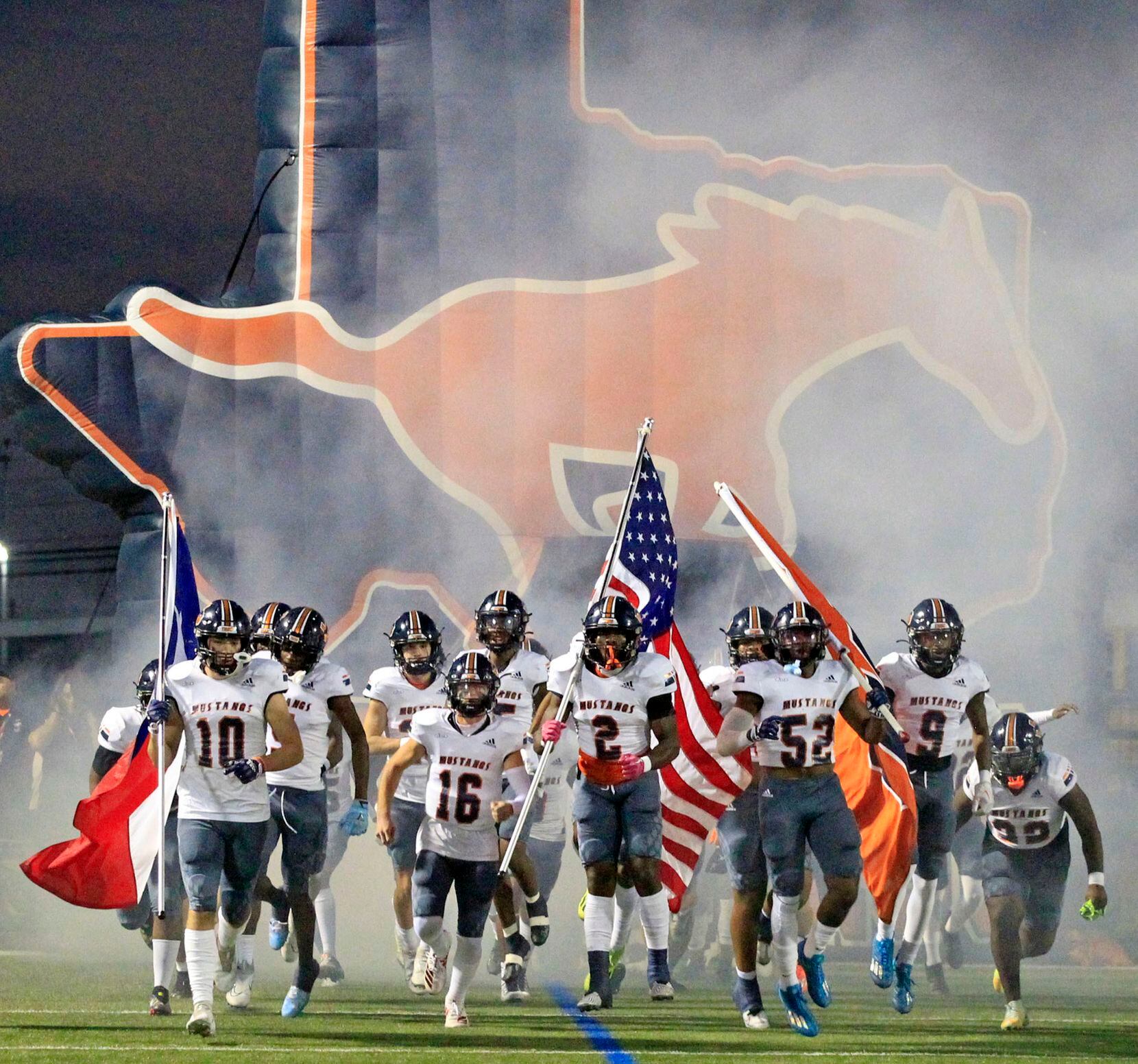 The Sachse Mustangs enter the field in a cloud of smoke before the start of a high school...