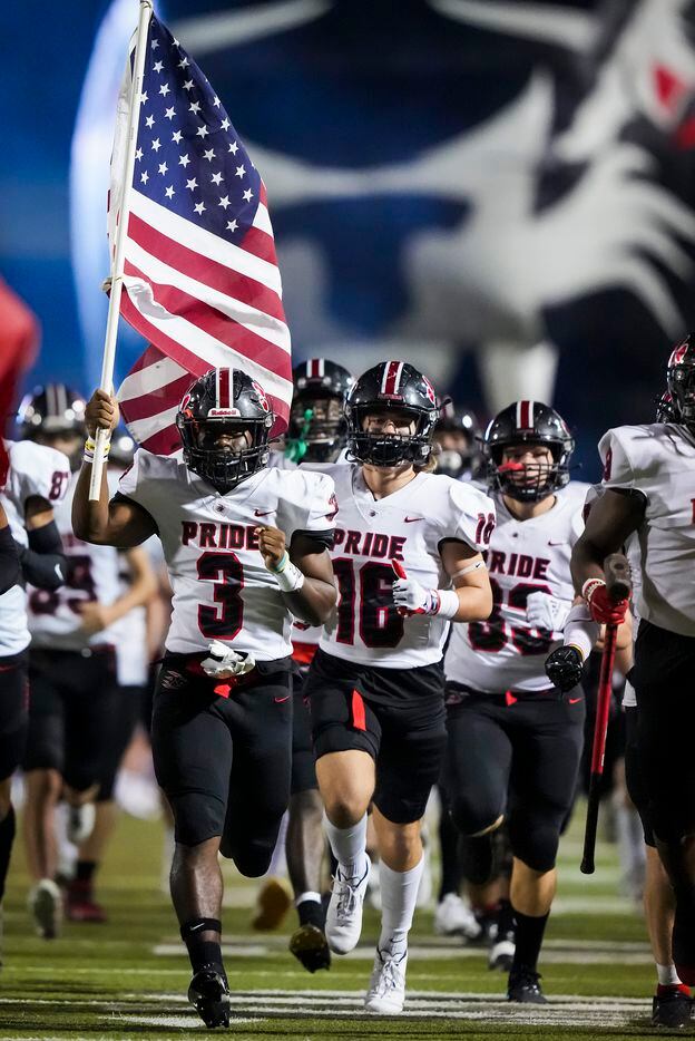 Colleyville Heritage running back Isaac Shabay (3) carries the stars and stripes as he leads the team onto the field for the first half of the Class 5A Division I Region I final against Mansfield Summit on Friday, Dec. 3, 2021, in North Richland Hills, Texas. (Smiley N. Pool/The Dallas Morning News)