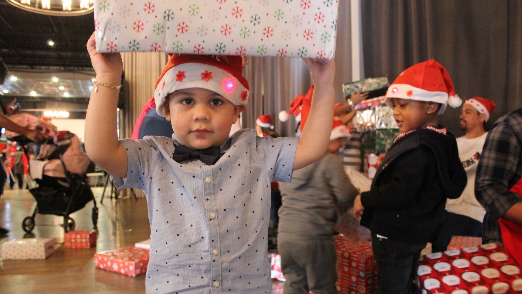 A child holds a wrapped present over his head during a holiday toy drive.