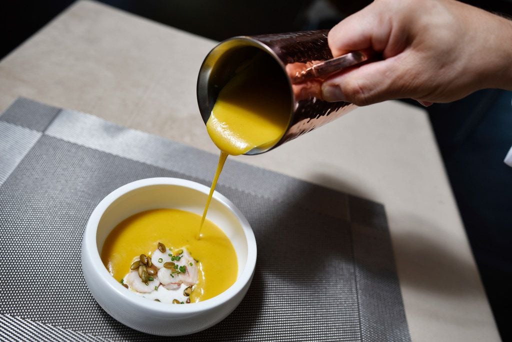 Executive Chef Eric Dreyer pours soup to complete a bowl of Delica Pumpkin Soup with poached...