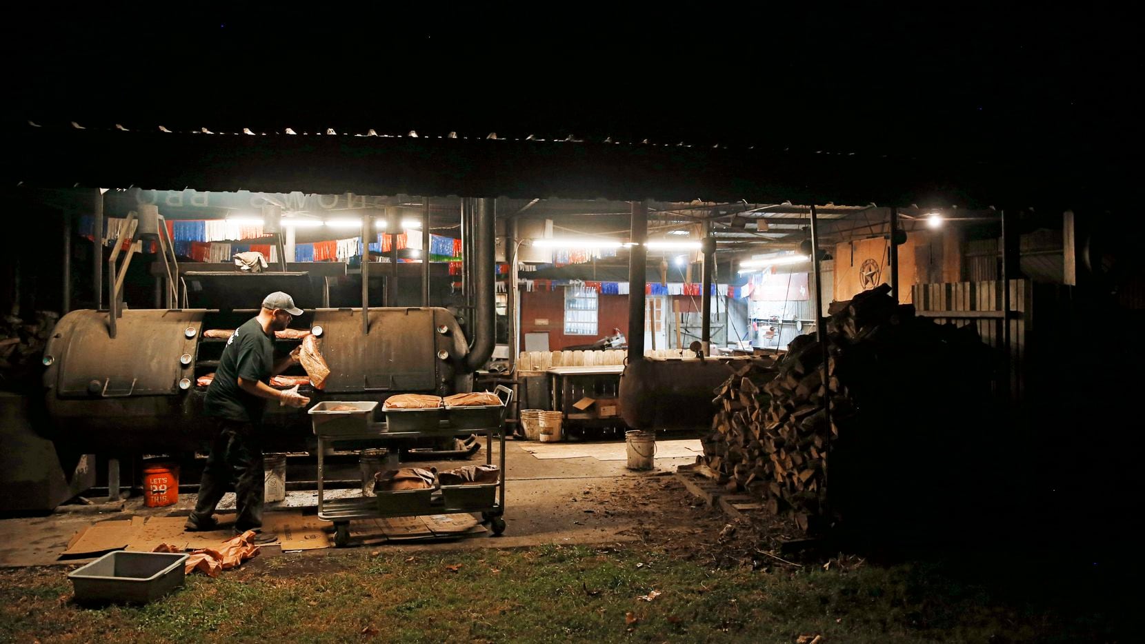Clay Cowgill works on putting the briskets on the smoker around 10 p.m. at Snow's BBQ in...