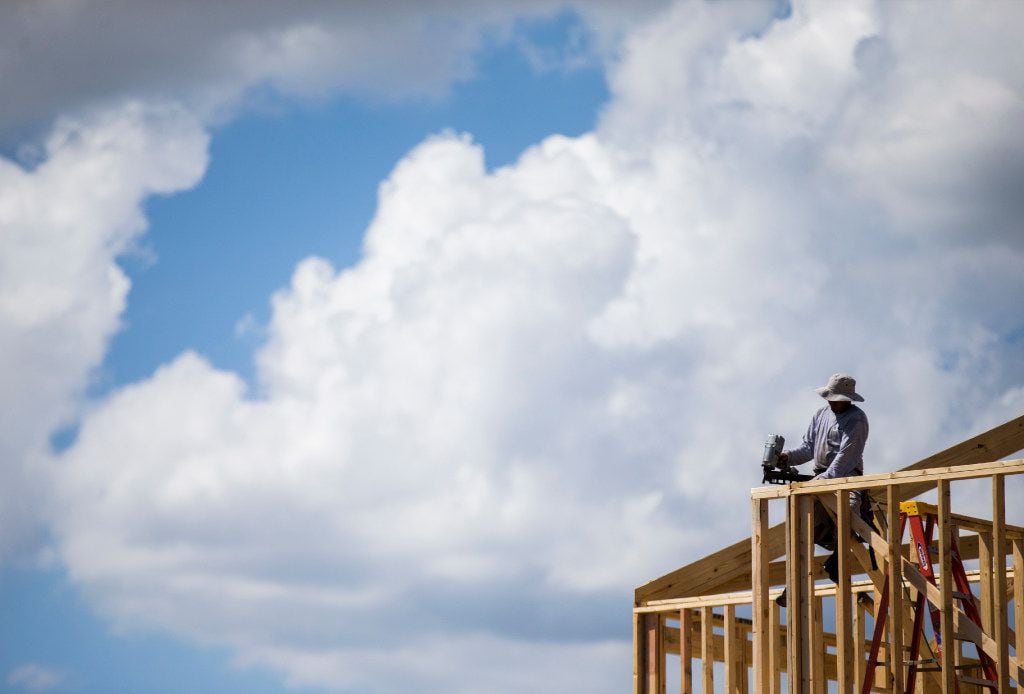 Construction workers frame new homes inside the Meritage Homes Villas at Las Colinas...