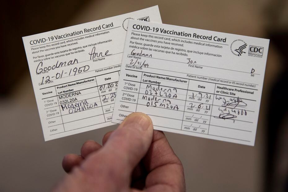 Jon Goodman holds up the COVID-19 vaccination record cards for him and his wife, Anne, at their home on Thursday, Feb. 25, 2021, in Fairview, Texas. The couple are both fully vaccinated from COVID-19, and they are looking forward to life post-vaccination. Avid motorcyclists, the pair put a pause on riding during the pandemic. “We thought even if we got into any small mishap, like even a scrape while riding, we’d be taking someone’s spot in the hospital who has COVID,” Jon said. “We decided to put off riding until it got safer.” (Lynda M. González/The Dallas Morning News)