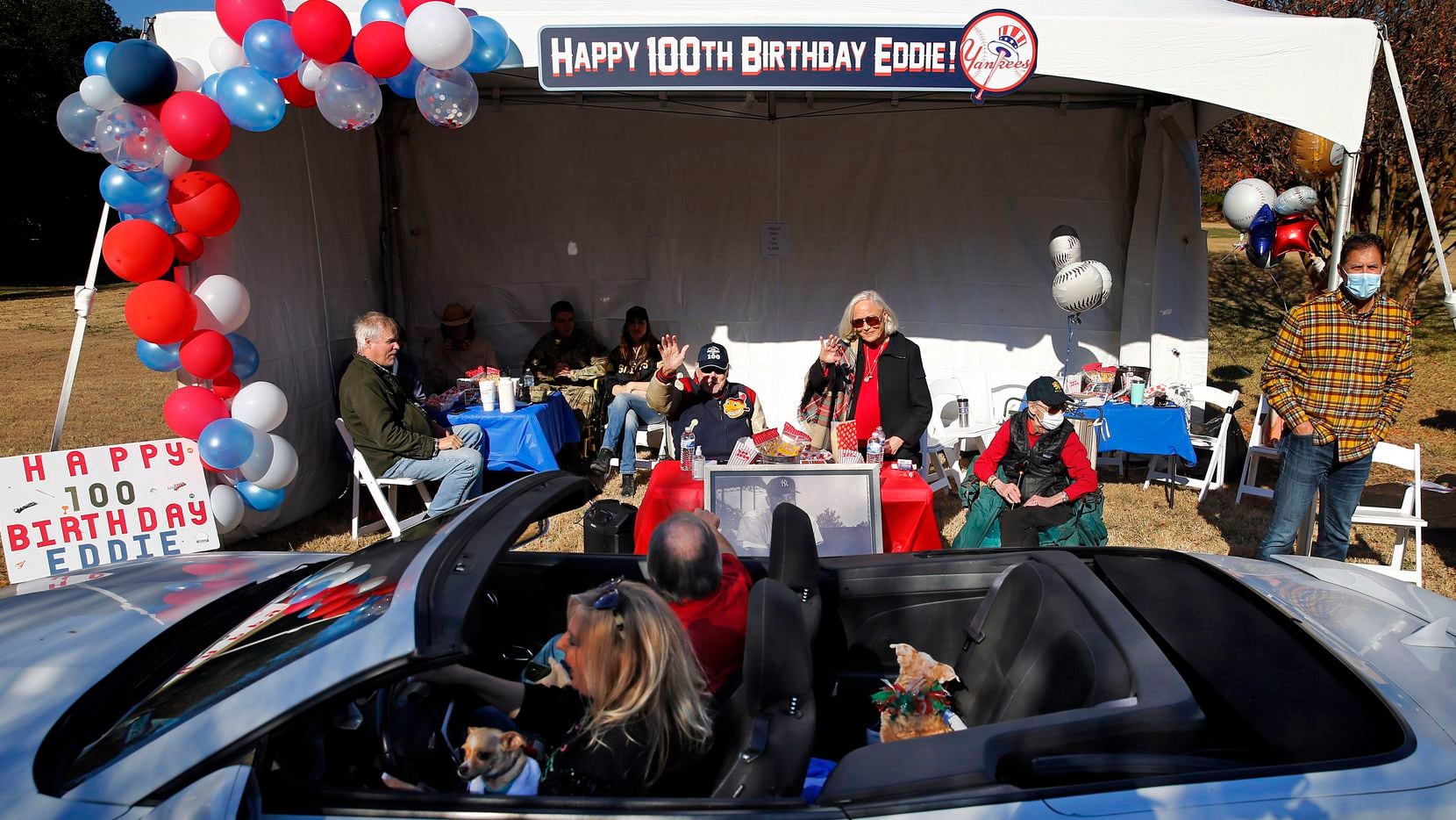 Eddie Robinson (seated)  waves to friends who deliver an early 100th birthday wish from...