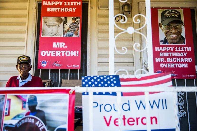 Richard Overton, 111, smokes a cigar on his front porch on May 25, among signs that were...