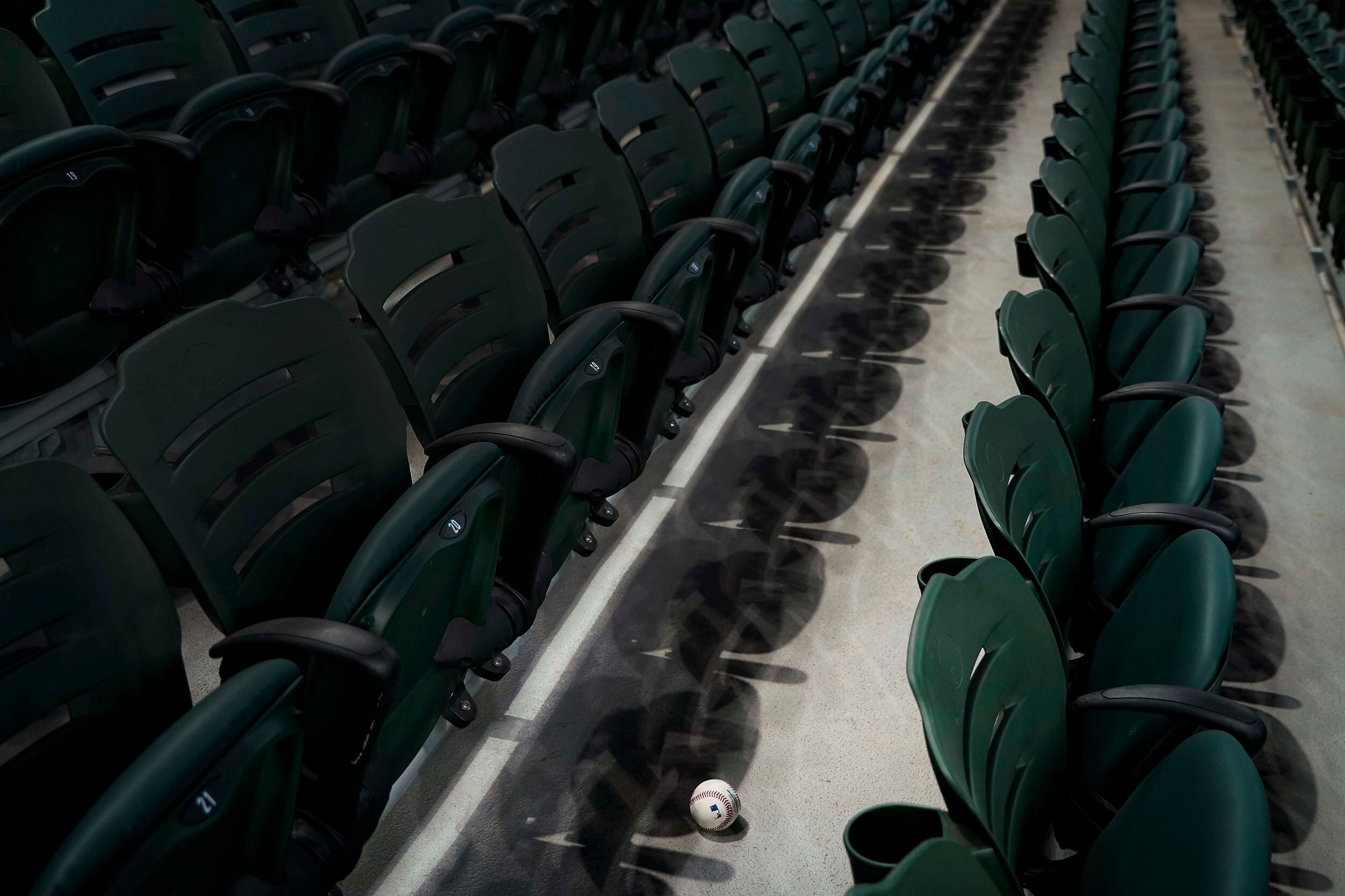 A baseball rests among empty rows of seats after being fouled off by a batter in an...