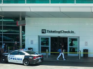 Passengers pass police tape as Dallas police investigate a scene Dallas Love Field Airport...