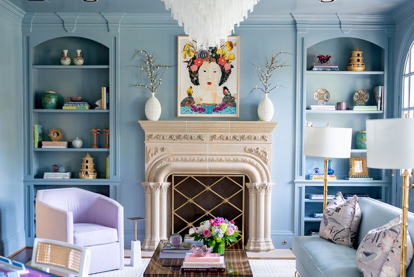 Light blue built-in wall bookshelves around a fireplace decorated with small keepsakes and...