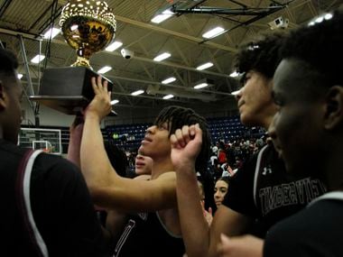 Mansfield Timberview players gather at mid-court as Joey Madimba raises the trophy after Timberview beat Mansfield Legacy 41-40 in overtime in Tuesday's Class 5A Region I quarterfinal.
