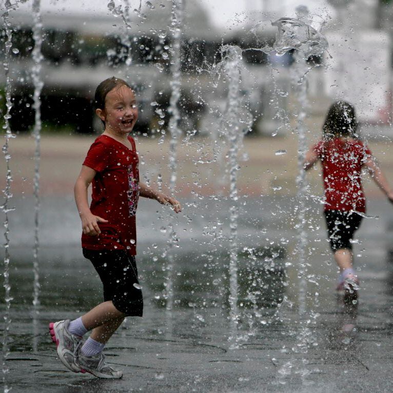 Sisters play in the spray fountains at Galatyn Park in Richardson.