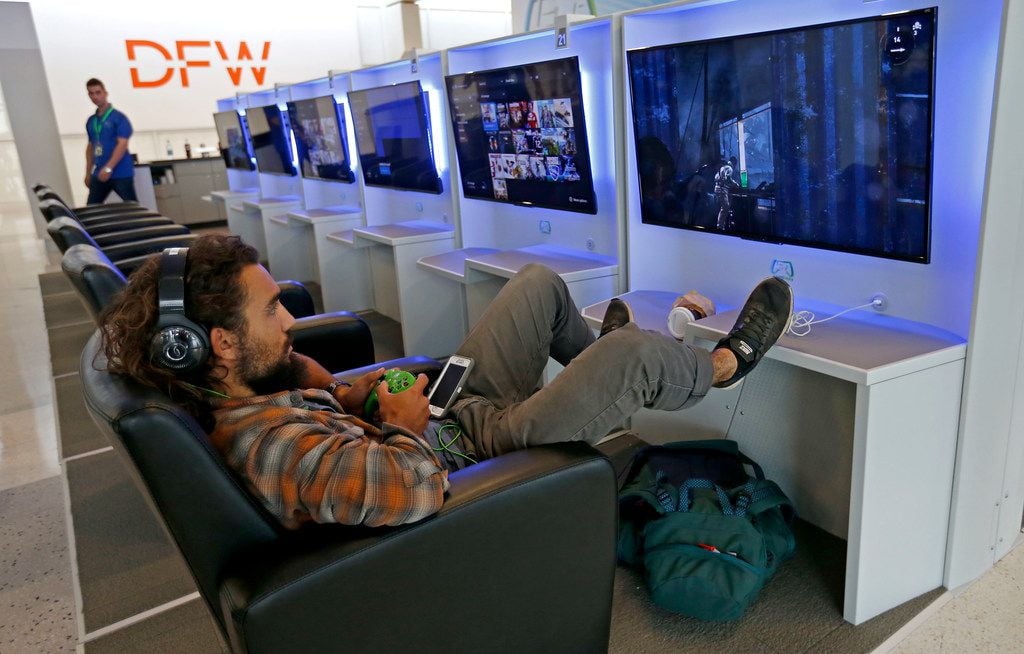 Traveler Conor Sandoval plays a video game at Gameway inside Terminal E of Dallas/Fort Worth International Airport in DFW Airport, Texas, Friday, July 6, 2018. He has a 22 hour layover heading to Chile from Seattle. 