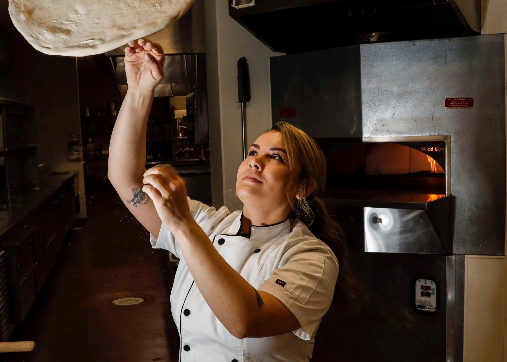 Michelle Tribble, executive chef of culinary development for Gordon Ramsay North America, tosses pizza dough in a kitchen at Dallas College's culinary facility in Dallas. Ramsay's company has partnered with Dallas College to use some of its test kitchens.