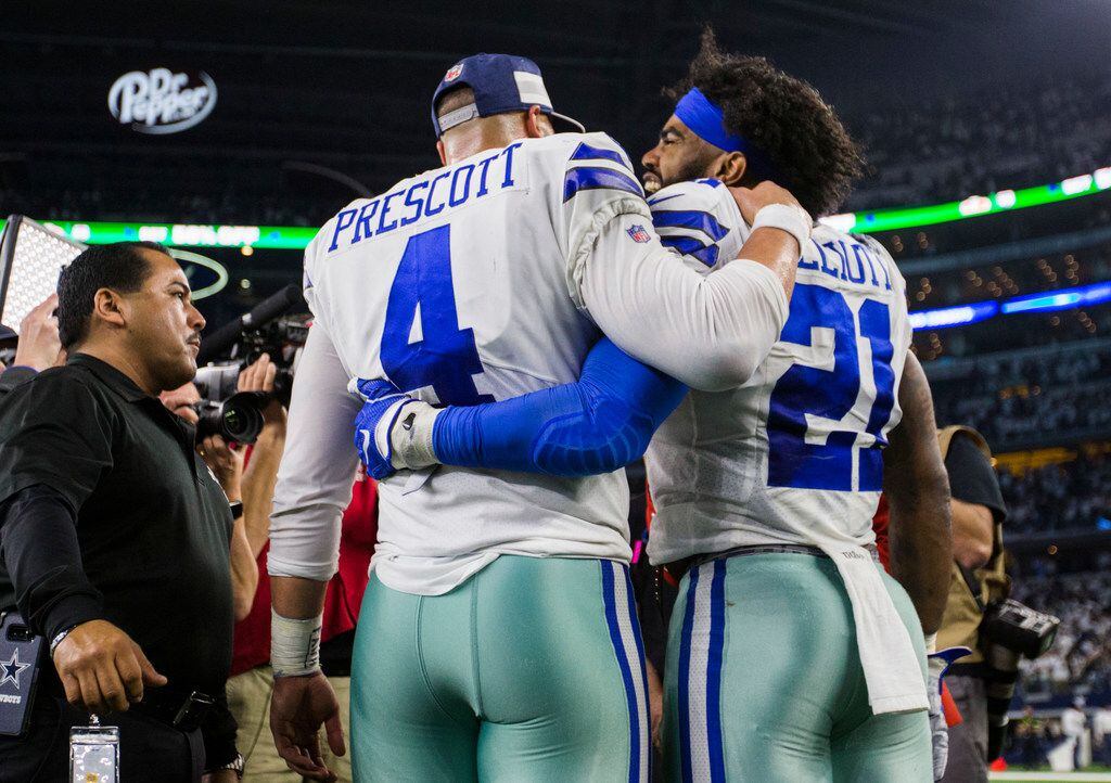 Dallas Cowboys quarterback Dak Prescott (4) hugs running back Ezekiel Elliott (21) after a...