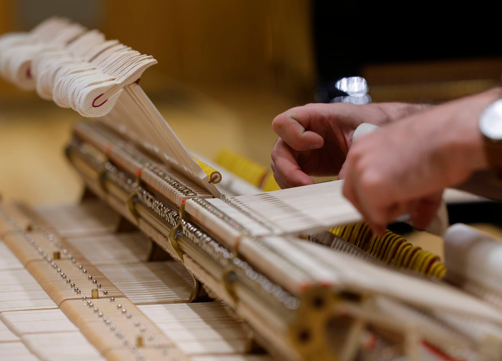Piano Technician Alex Moore adjusts the hammers on one of the Steinway Pianos before...