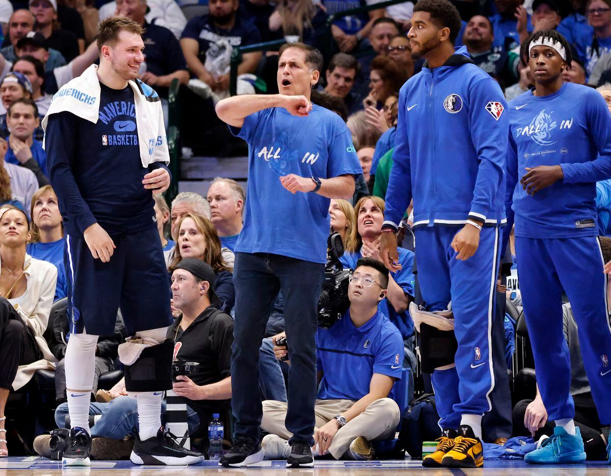 Dallas Mavericks owner Mark Cuban (center) calls on the official for a foul as guard Luka...