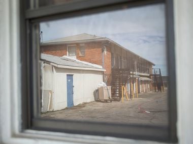The two-story building of Cole Manor Motel is reflected on a motel window.