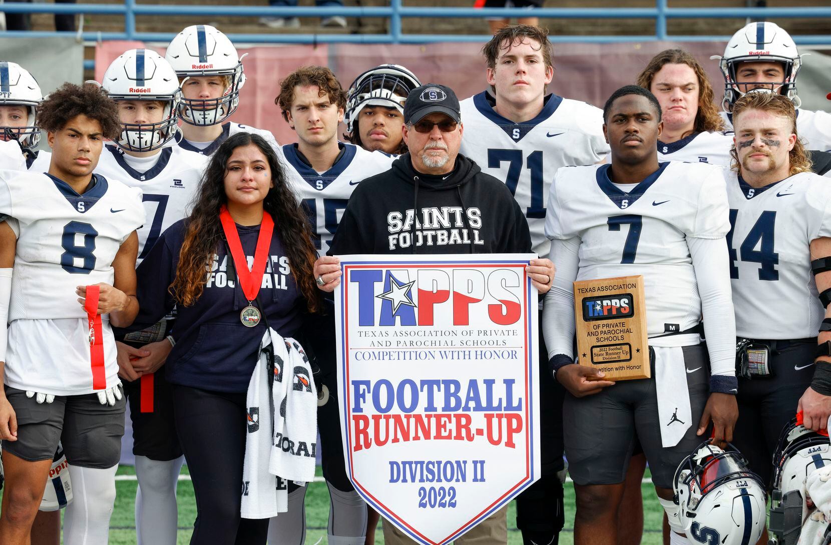 Fort Worth All Saints head coach Aaron Beck holds the TAPPS Division II runner-up banner...