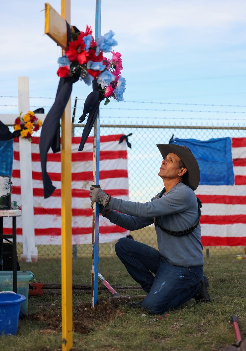 Artist Roberto Márquez places the second of six painted crosses into the ground as part of a...