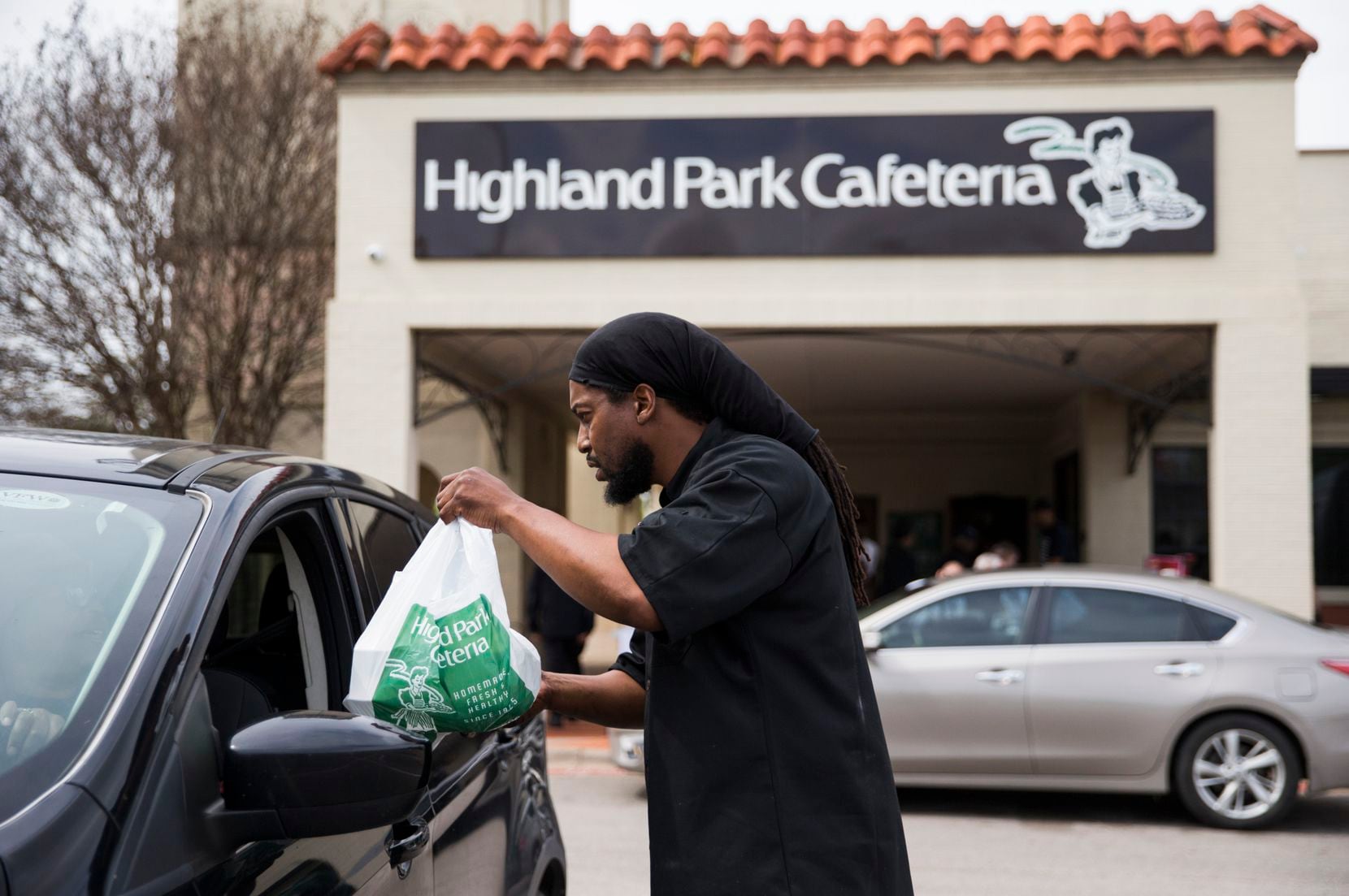 Executive Chef Johnny Howard delivers a meal to a driver outside Highland Park Cafeteria on Wednesday, March 18, 2020 in Dallas. Employees handed out free meals outside the restaurant after Dallas restaurants and bars were closed due to the spread of COVID-19. 