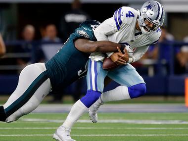 Dallas Cowboys quarterback Dak Prescott (4), right, hangs onto the football after being hit...