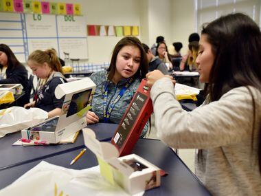 Students Dafne Sanchez, left, and Sandra Sanchez, look over their free tablets after...