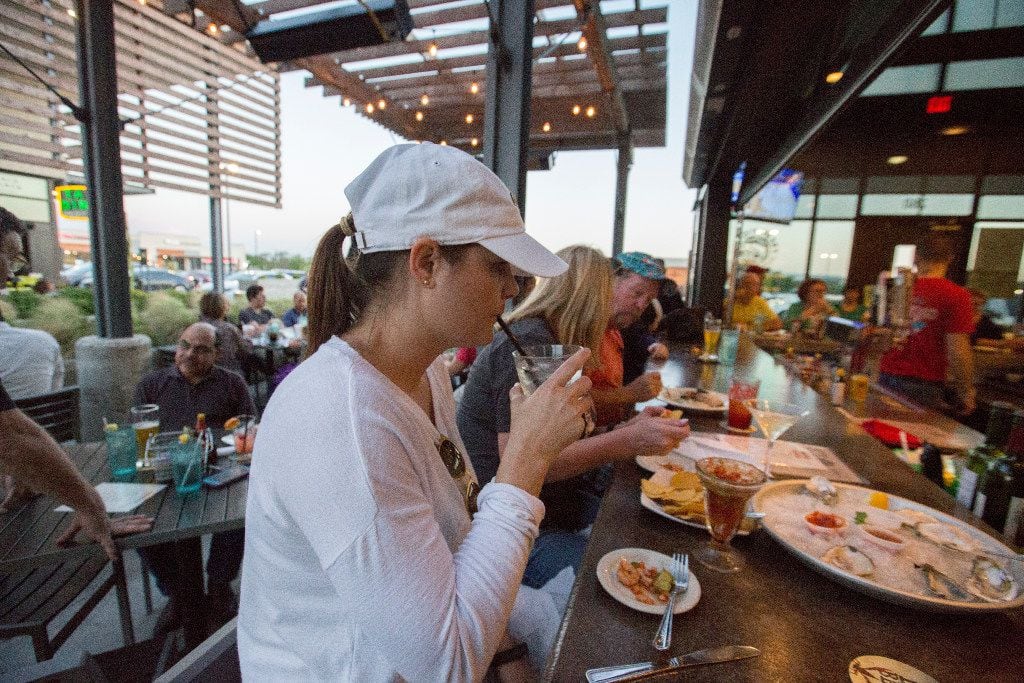 Dana Eldridge, center, takes a sip of her drink at the peninsula bar Fish City Grill in...