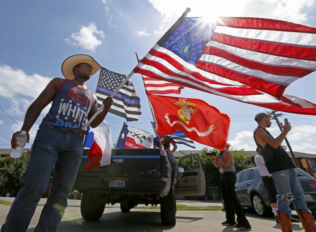 Counter protester Joseph Offutt (left) holds an American flag in a group of counter protest...