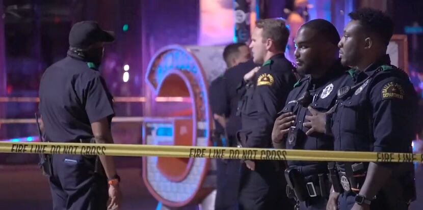 Dallas police officers survey the scene after one person was killed and five others were...