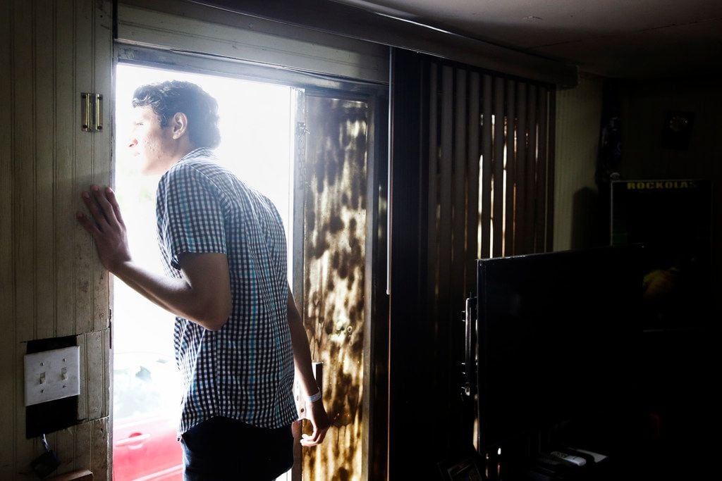 Francisco Galicia peers out the front door of his family's Edinburg home, curious which news...
