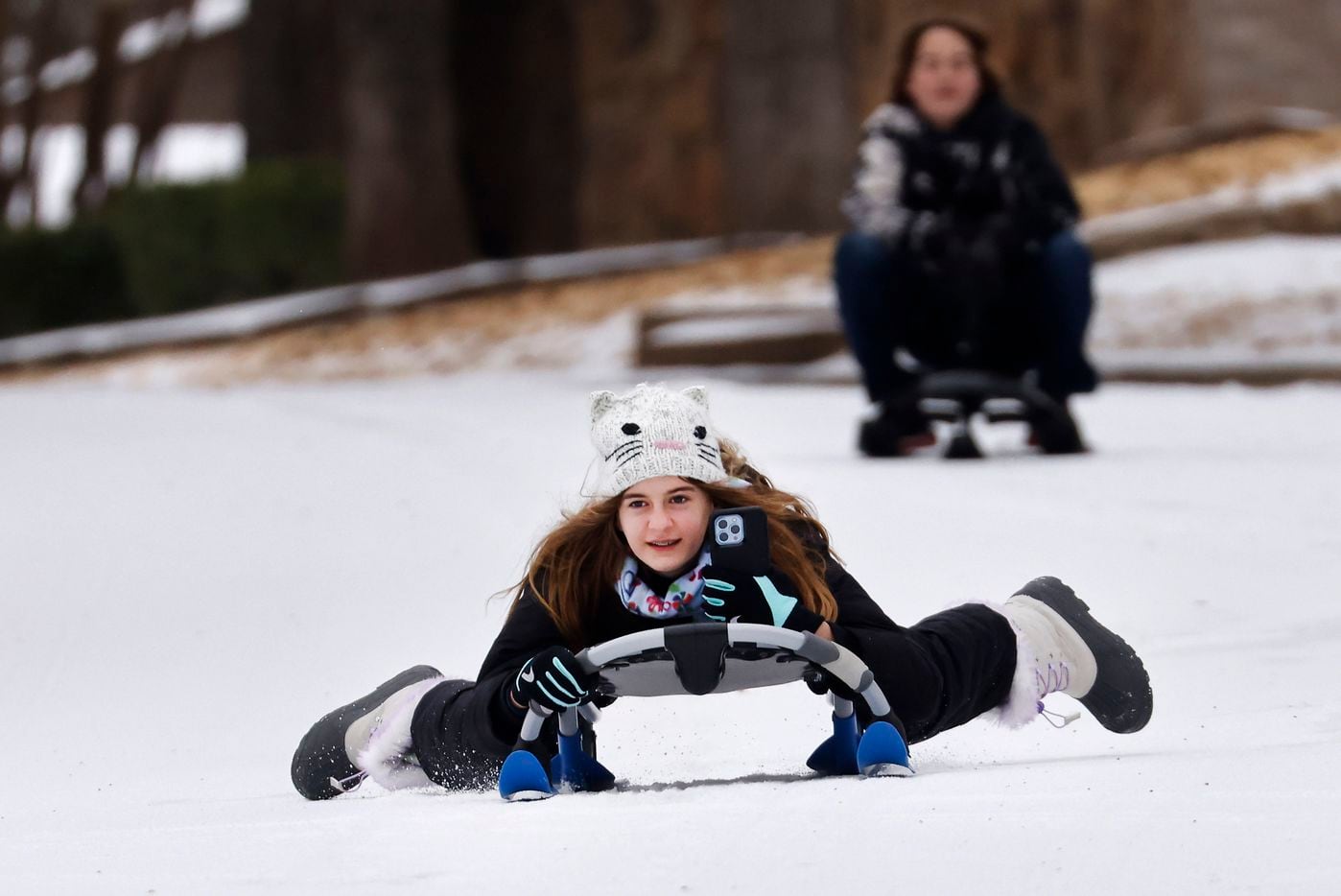 Julia Schack and her brother Jonathan sled down an icy street in N. Arlington, Texas, after...