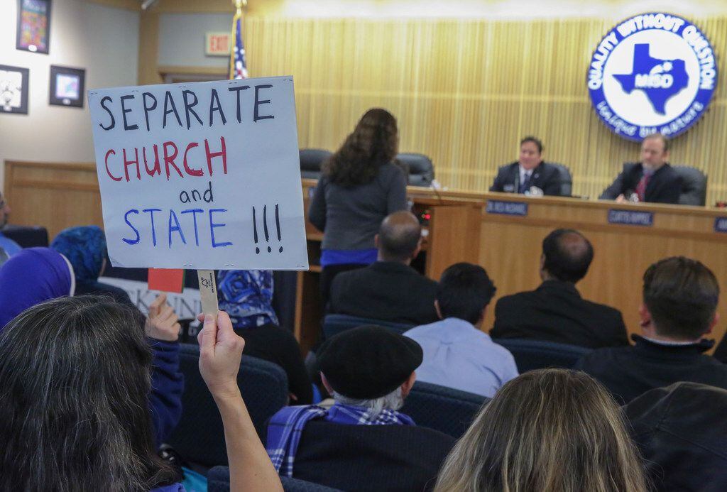 Kristy Fuxa holds a separate church and state sign while Amy Bennett speaks at the McKinney...