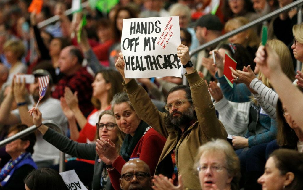 People cheer after a question about the Affordable Care Act during a town hall meeting with...