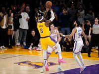 Los Angeles Lakers forward LeBron James, left, scores to pass Kareem Abdul-Jabbar to become...