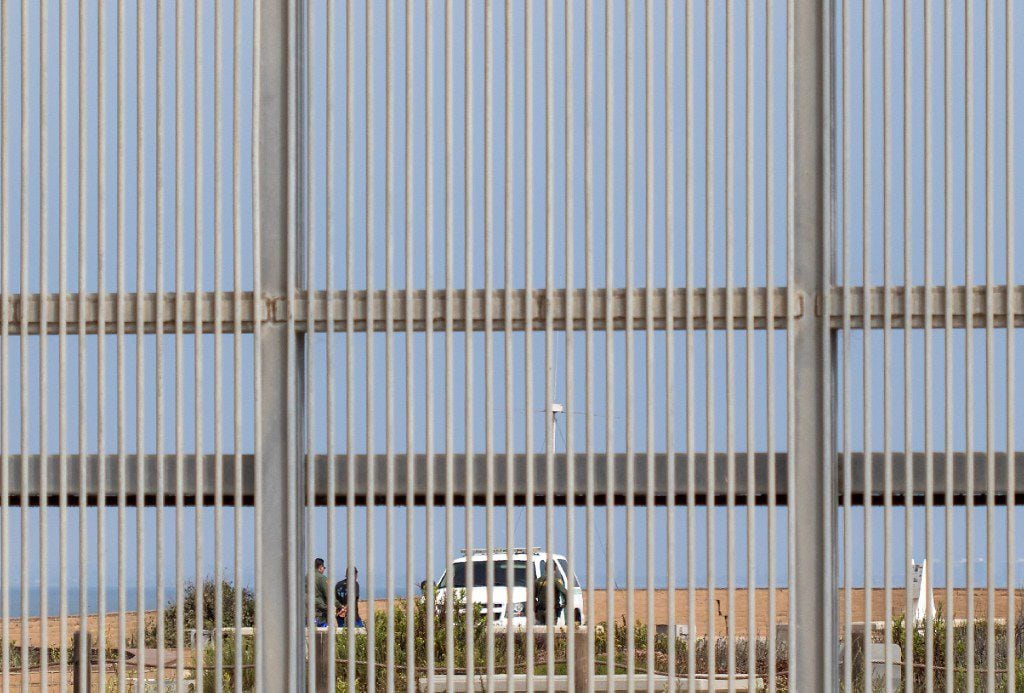 Border patrol officers are seen through the Border Field Park border fence in Tijuana on August 22, 2017.
